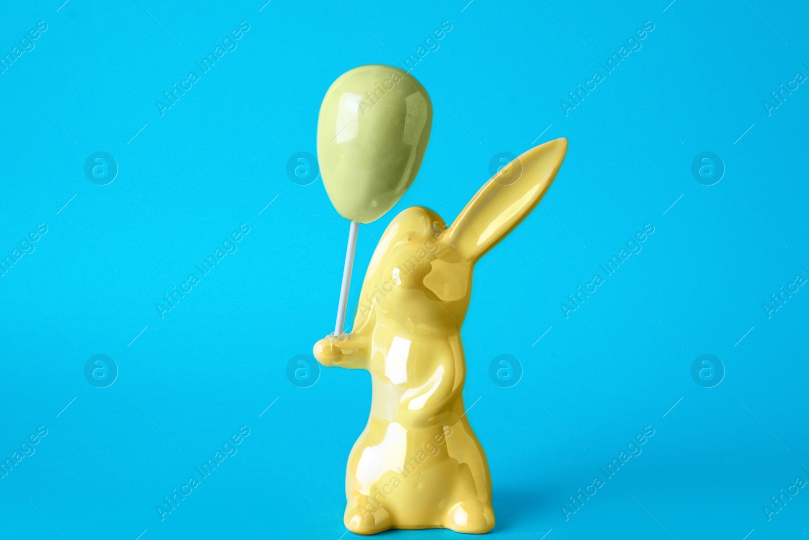 Photo of Bunny ceramic figure as Easter decor on blue background