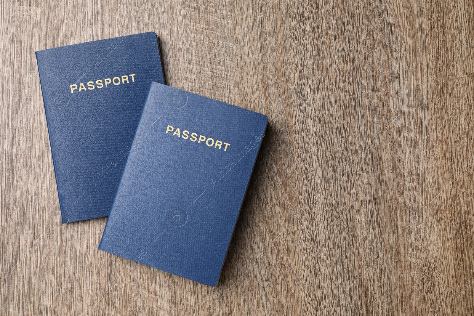 Photo of Blank blue passports on wooden table, flat lay with space for text