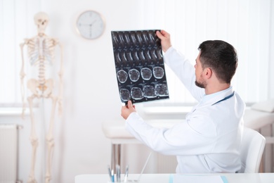 Photo of Orthopedist examining X-ray picture at desk in clinic