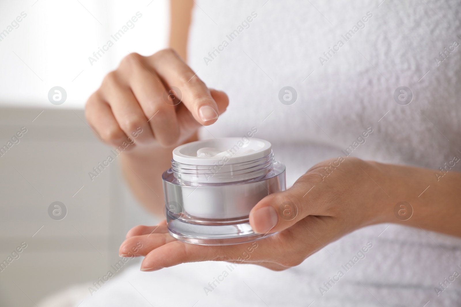 Photo of Woman with jar of moisturizing cream on blurred background, closeup