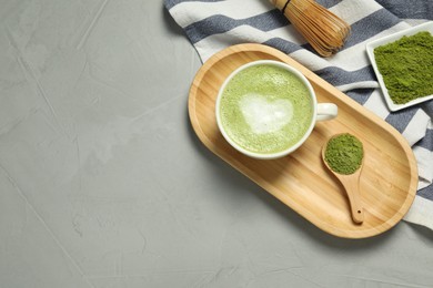 Cup of fresh matcha latte and powder on grey table, flat lay. Space for text