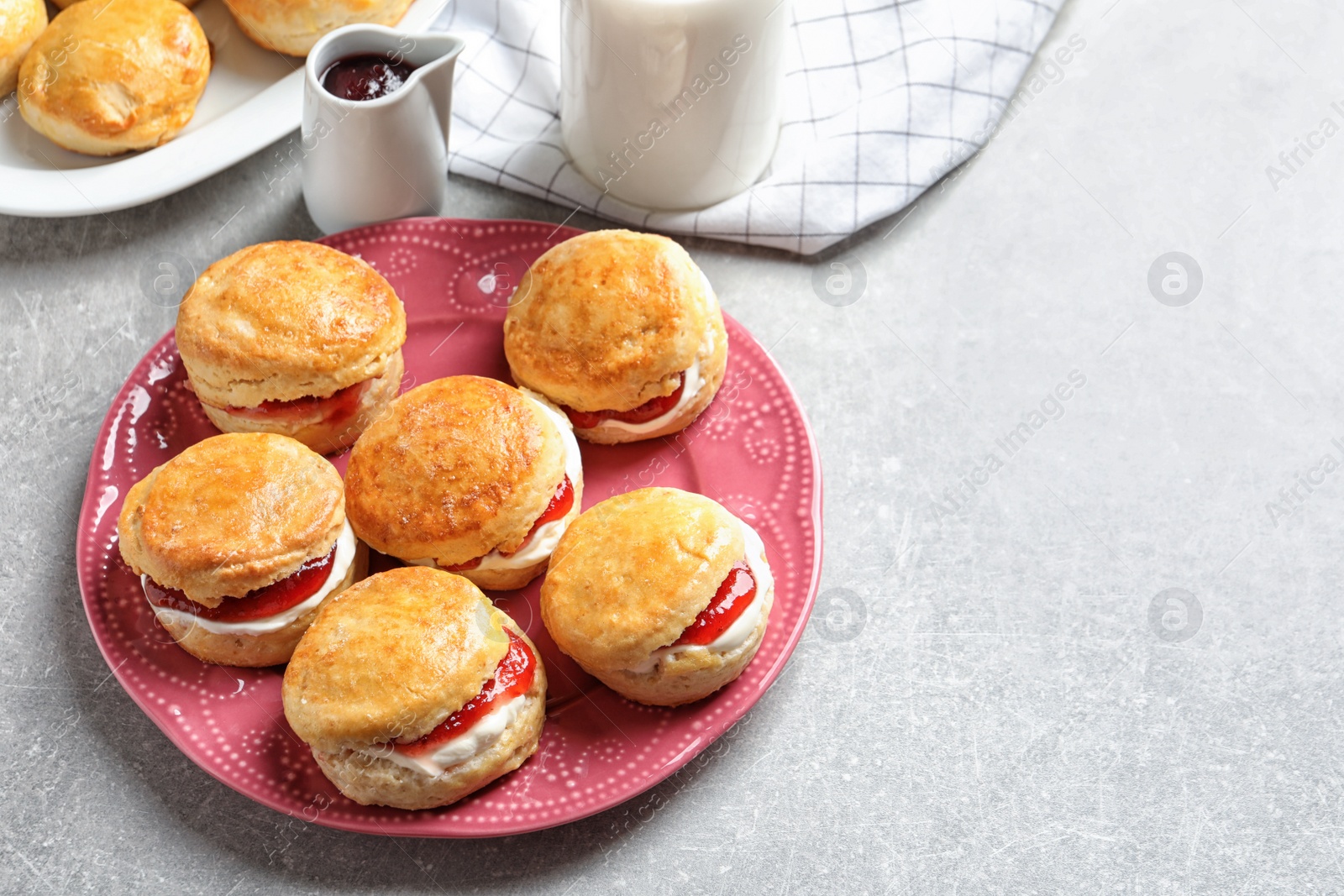 Photo of Tasty scones with clotted cream and jam on light background