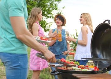 Young people having barbecue with modern grill outdoors