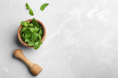 Fresh mint with mortar and pestle on grey marble background, flat lay. Space for text