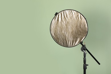 Photo of Studio reflector on pale green background, space for text. Professional photographer's equipment