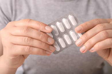 Woman holding blister of white pills, closeup