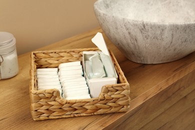 Photo of Wicker basket with different tampons on wooden countertop in bathroom. Menstrual hygienic product