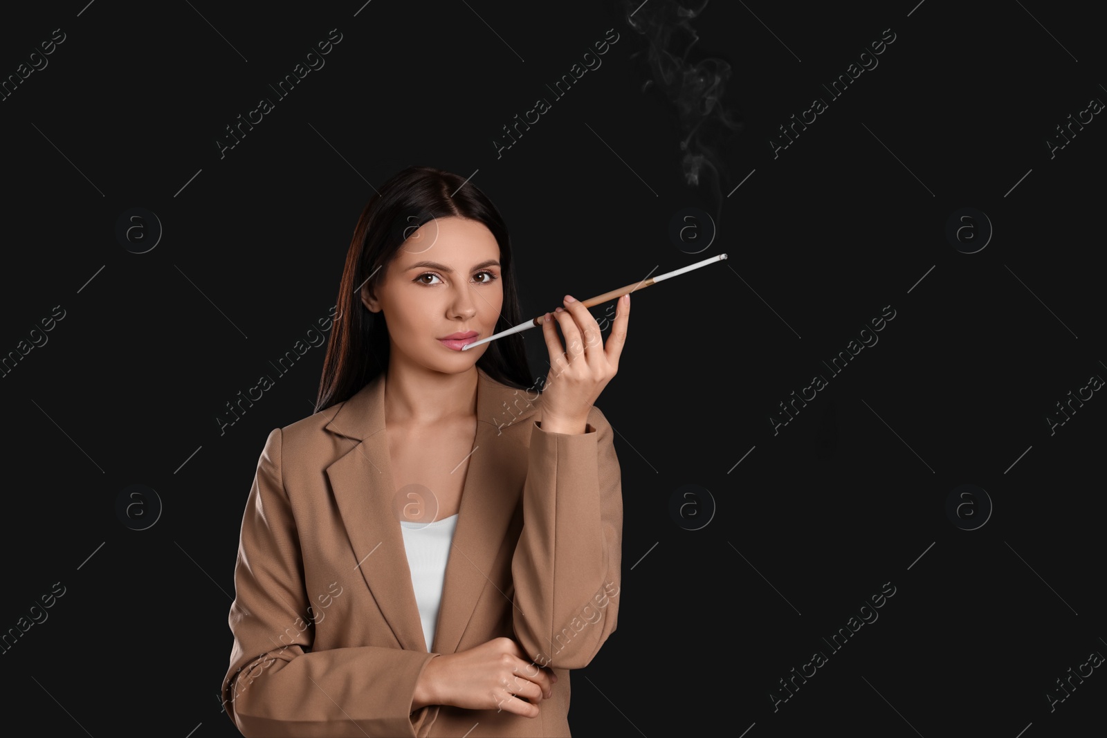 Photo of Woman using long cigarette holder for smoking on black background, space for text