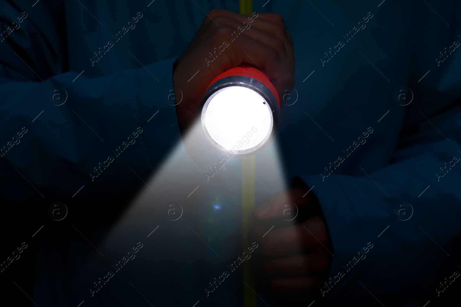 Image of Man with bright flashlight in darkness, closeup