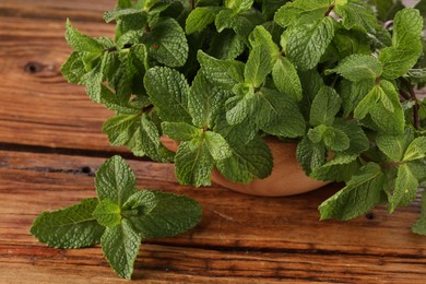 Photo of Bowl with fresh green mint leaves on wooden table, closeup