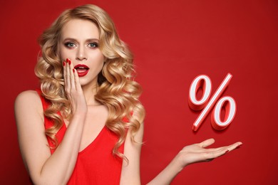 Image of Surprised woman pointing at sign Percent on red background. Special promotion