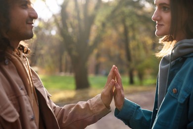 Photo of Young couple holding hands together in autumn park, closeup. Dating agency