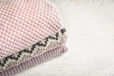 Photo of Stack of warm knitted clothes on light background, closeup