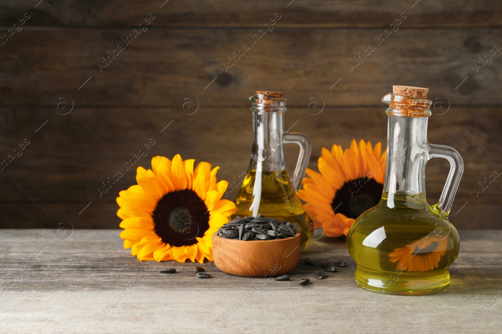 Photo of Sunflower cooking oil, seeds and yellow flowers on wooden table