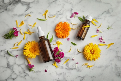 Flat lay composition with essential oils and flowers on marble background