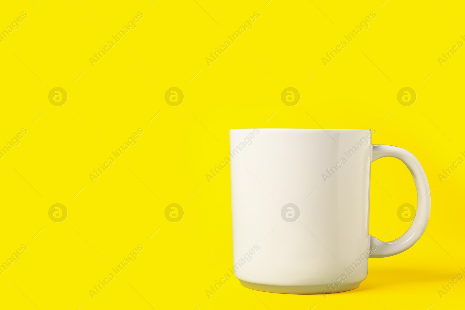 Photo of One white ceramic mug on yellow background, space for text