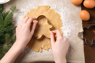 Woman making Christmas cookies with cutters at wooden table, top view