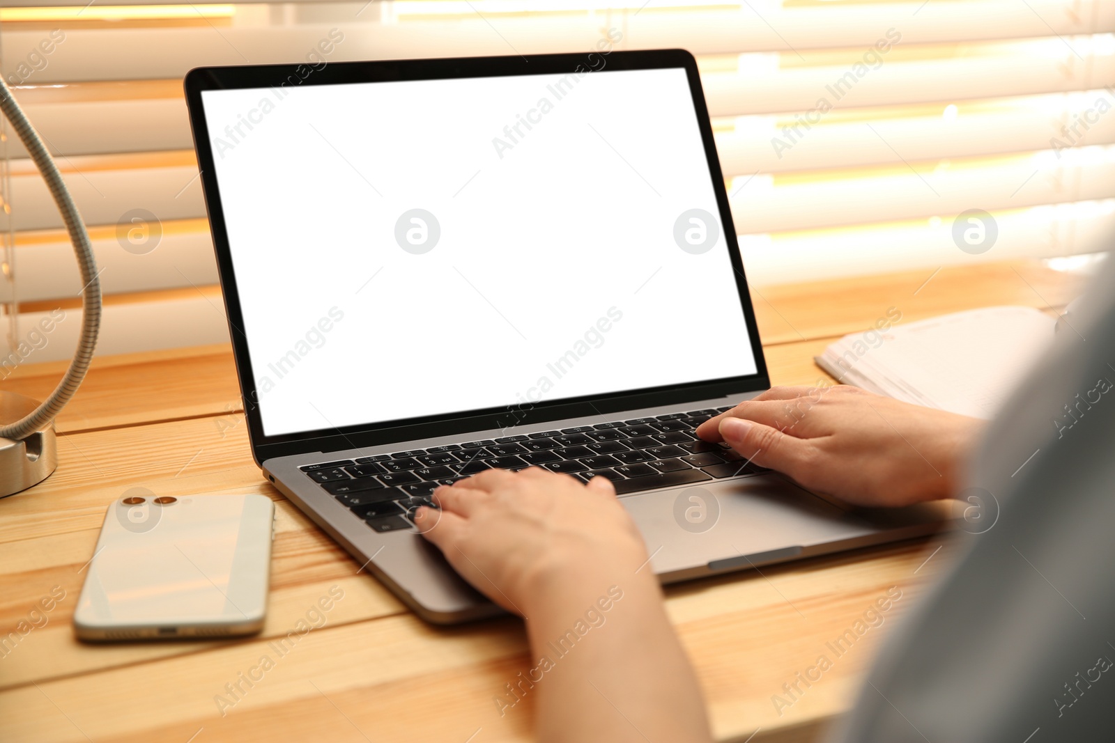 Photo of Woman working with modern laptop at wooden table, closeup. Space for design