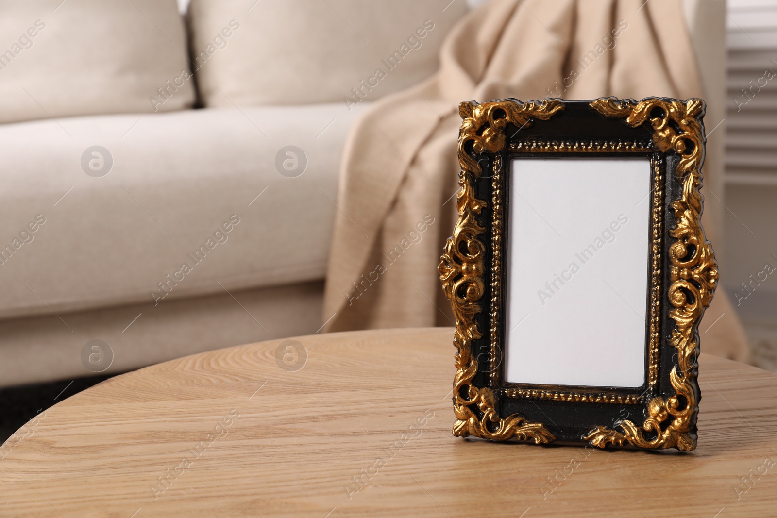Photo of Beautiful vintage empty frame on wooden coffee table indoors, space for text