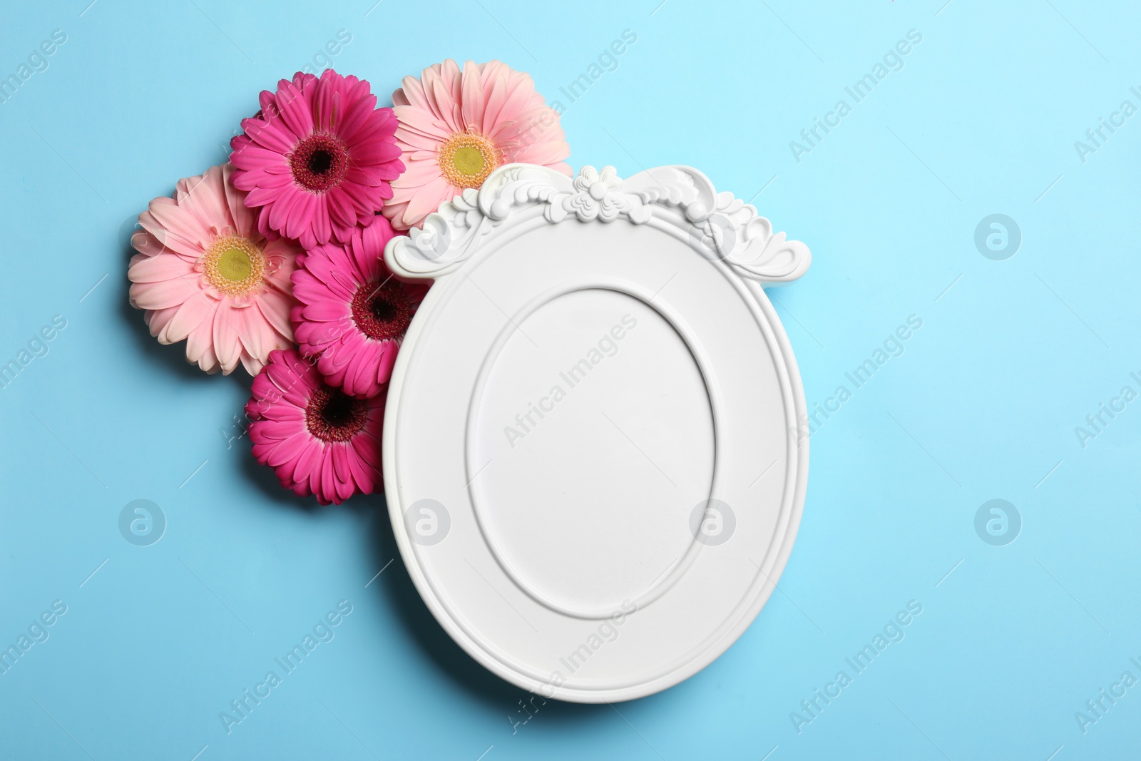 Photo of Empty photo frame and flowers on color background, top view. Space for text