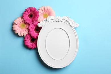 Photo of Empty photo frame and flowers on color background, top view. Space for text