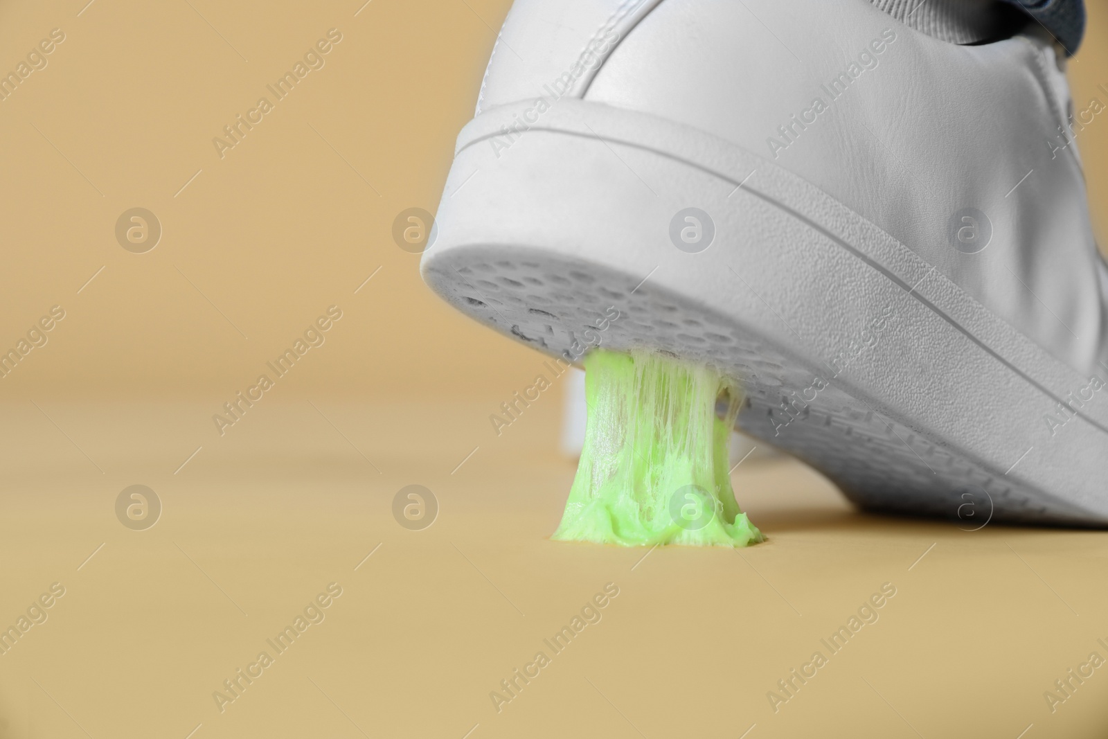 Photo of Person stepping into chewing gum on light brown background, closeup. Space for text