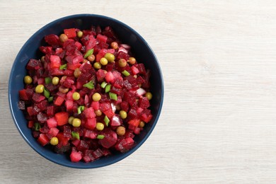 Bowl of delicious fresh vinaigrette salad on white wooden table, top view. Space for text