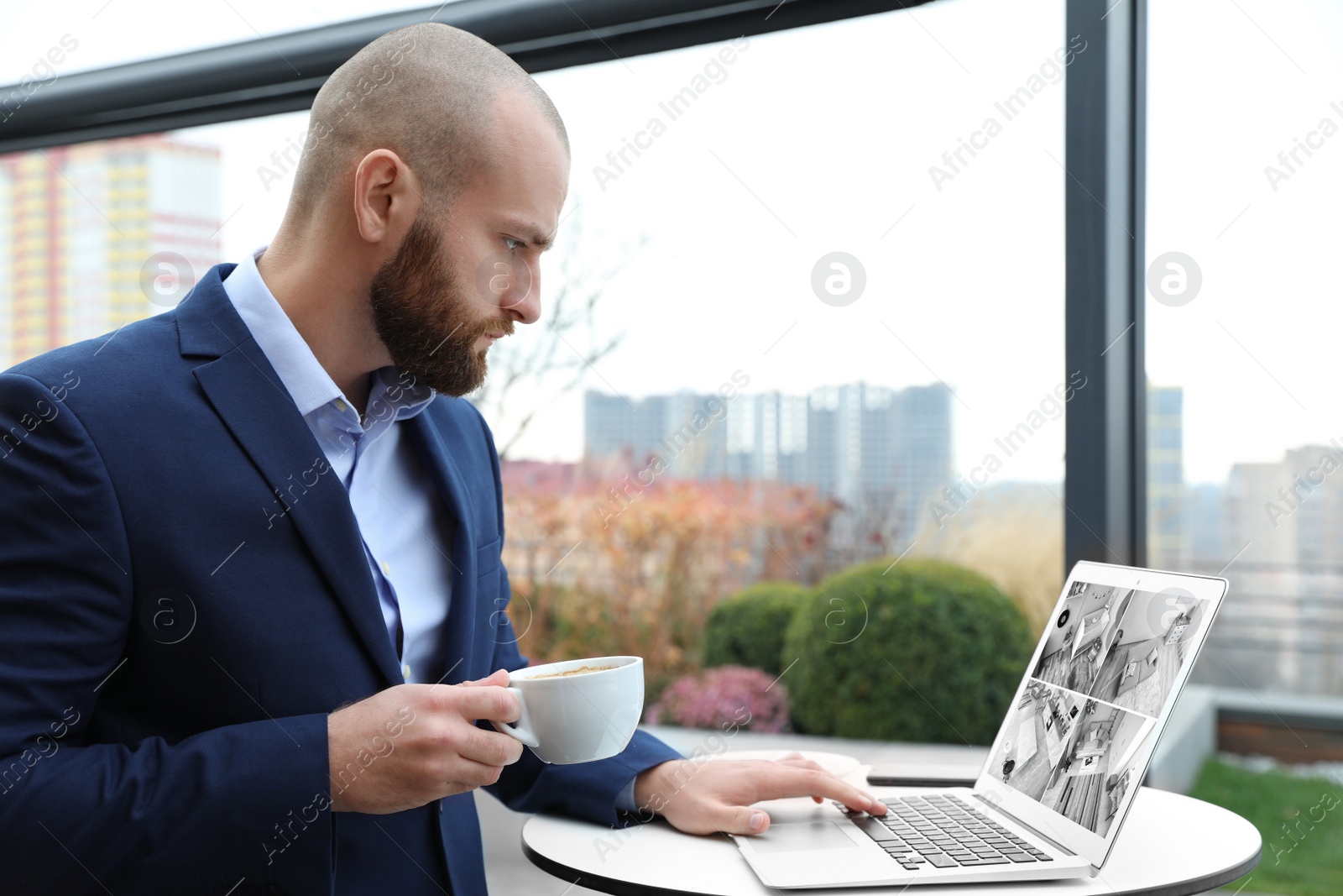Image of Man monitoring modern cctv cameras on laptop indoors. Home security system