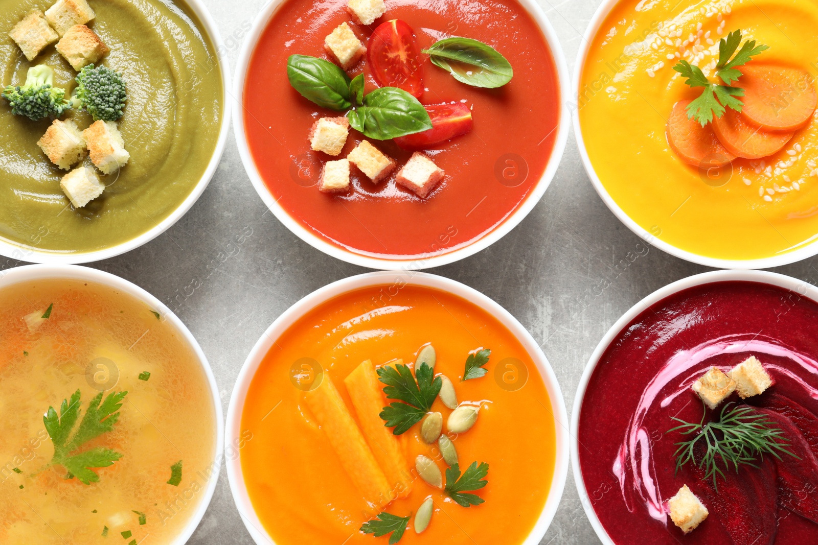 Photo of Various cream soups in bowls on grey background, top view