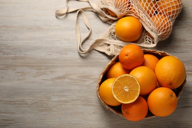 Many whole and cut oranges on wooden table, flat lay. Space for text