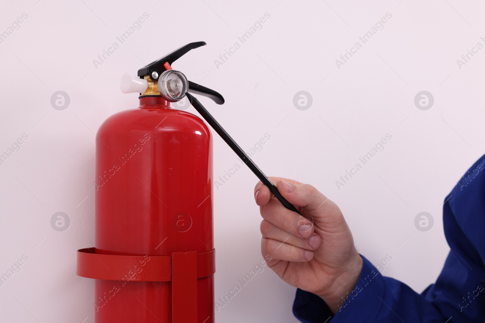 Photo of Man checking quality of fire extinguisher indoors, closeup
