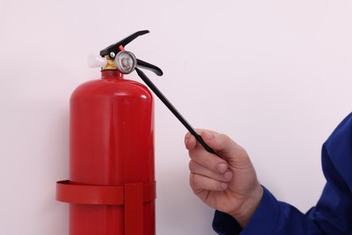 Photo of Man checking quality of fire extinguisher indoors, closeup