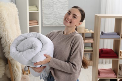Smiling young woman with duvet in home textiles store
