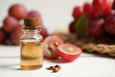 Photo of Bottle of natural grape seed oil on white wooden table, space for text. Organic cosmetic