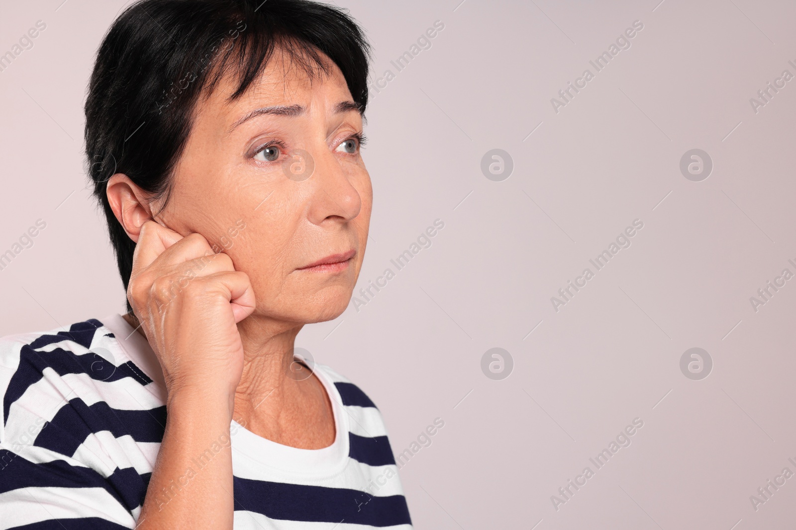 Photo of Senior woman suffering from ear pain on light grey background. Space for text