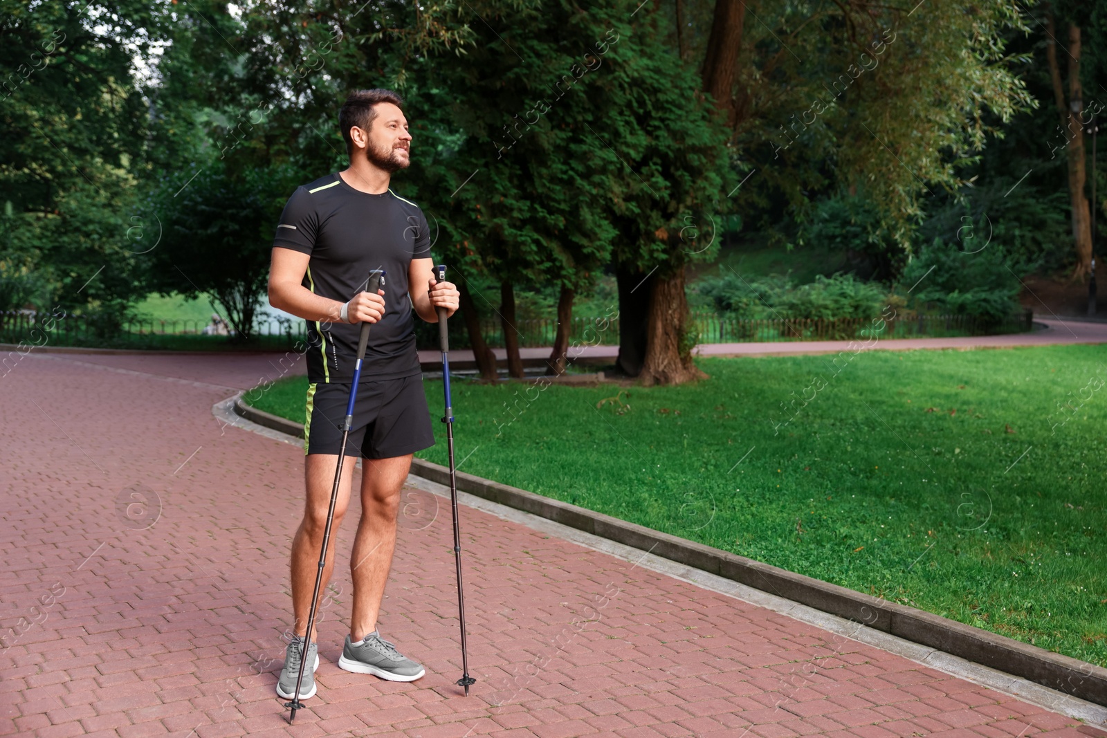 Photo of Man practicing Nordic walking with poles outdoors. Space for text