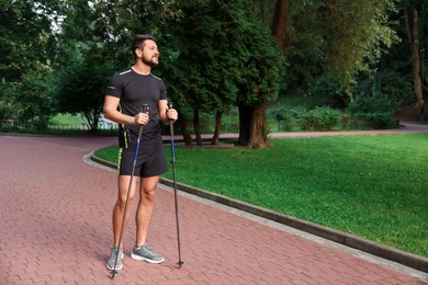 Man practicing Nordic walking with poles outdoors. Space for text