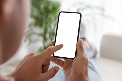 Man using mobile phone with empty screen indoors, closeup