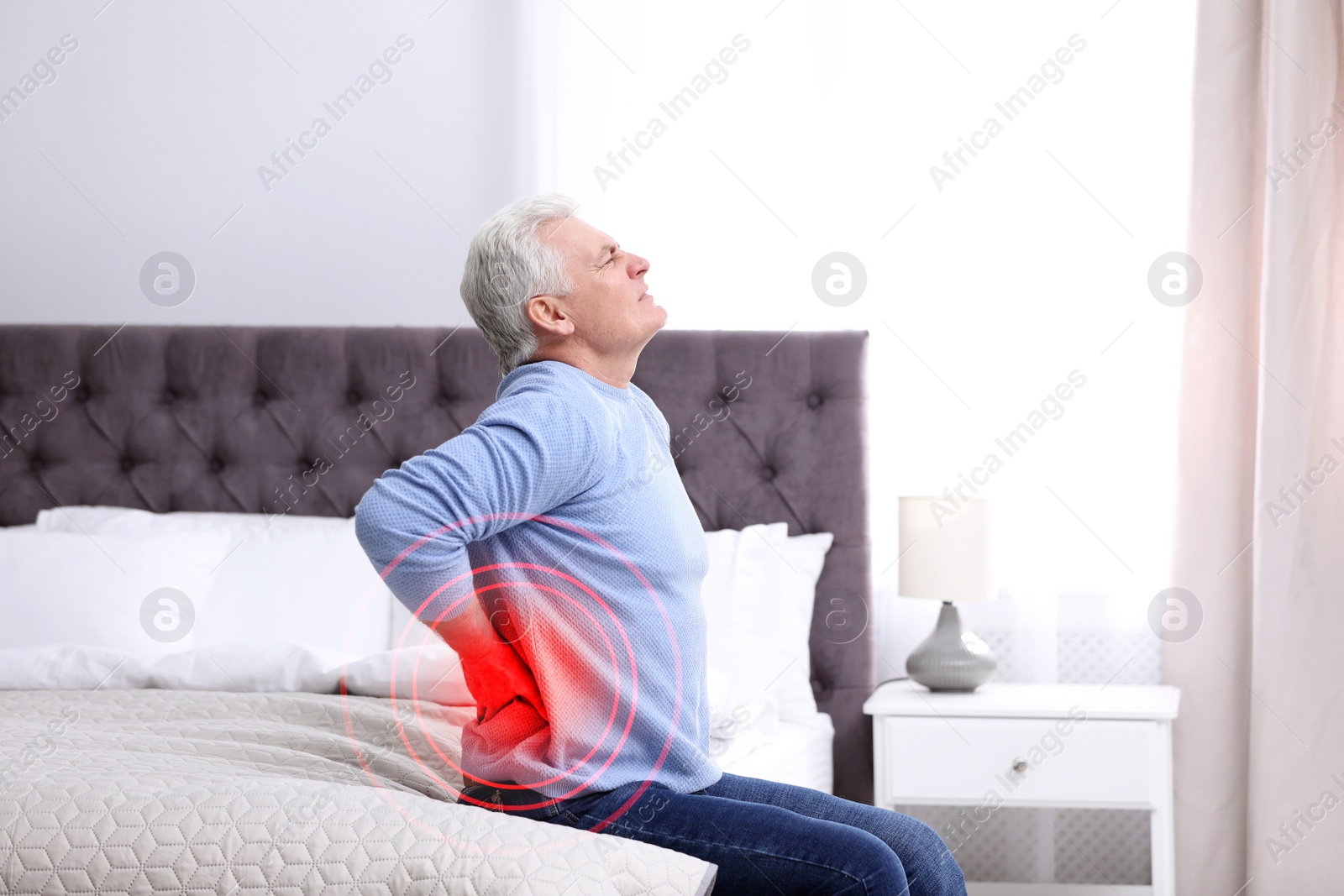 Image of Senior man suffering from back pain after sleeping on uncomfortable mattress at home