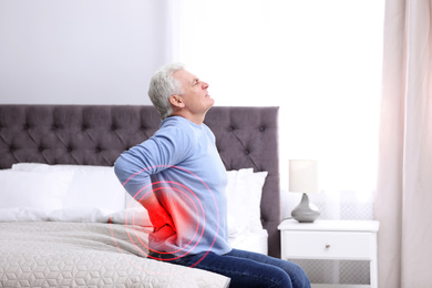 Image of Senior man suffering from back pain after sleeping on uncomfortable mattress at home