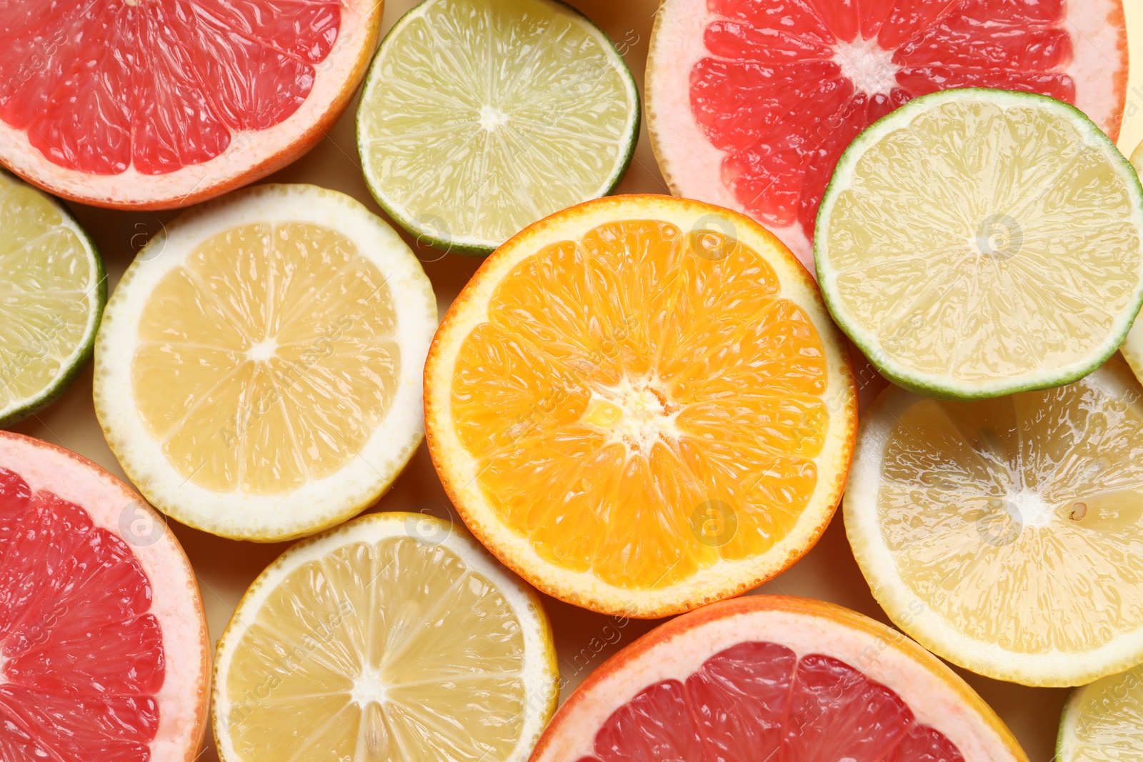 Photo of Different cut citrus fruits on beige table, flat lay