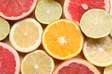 Photo of Different cut citrus fruits on beige table, flat lay