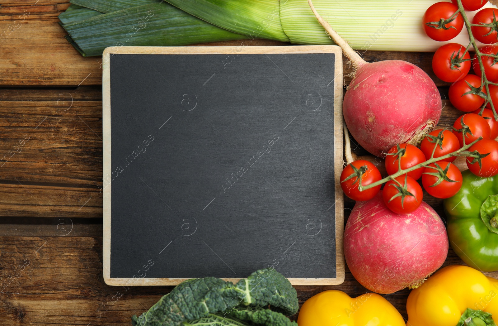 Photo of Blank chalkboard surrounded by different fresh vegetables on wooden table, flat lay with space for text. Cooking classes