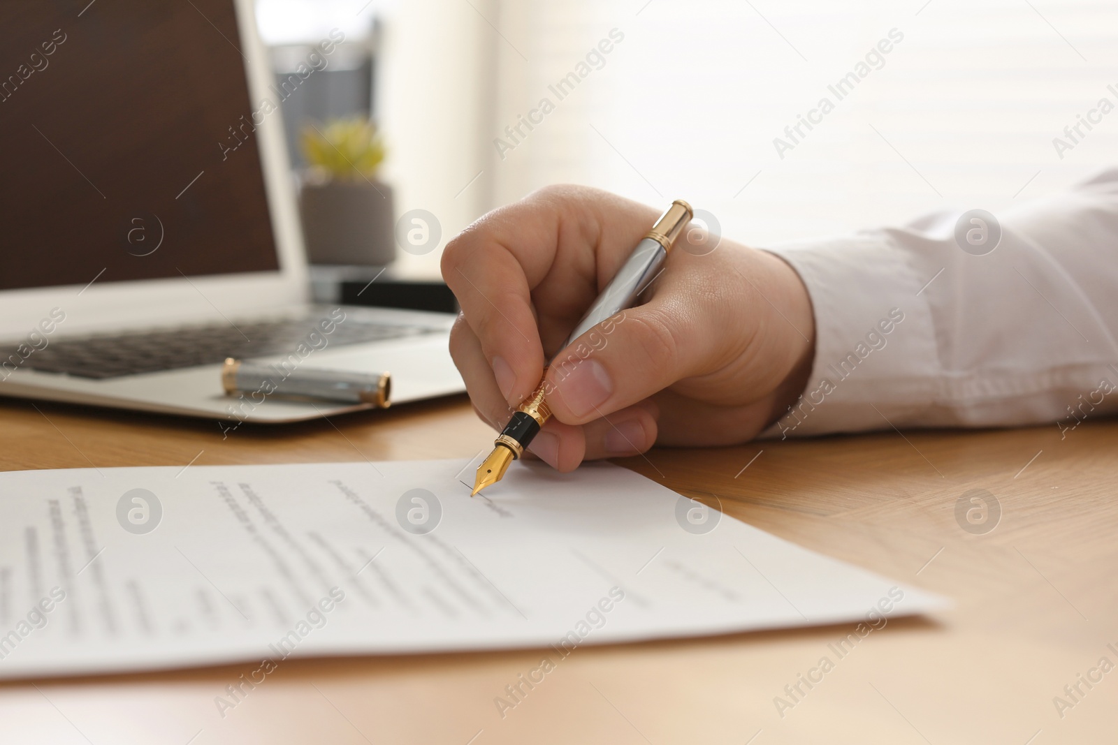 Photo of Notary signing document at wooden table, closeup