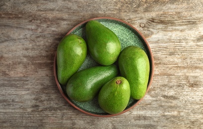 Photo of Plate with ripe avocados on wooden background, top view