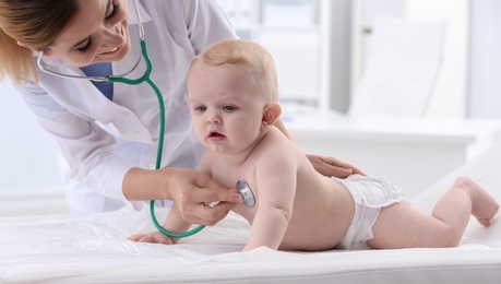 Photo of Children's doctor examining baby with stethoscope in hospital