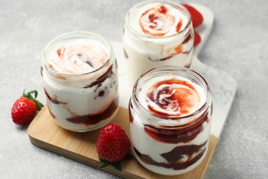 Photo of Tasty yoghurt with jam and strawberries on grey table, closeup