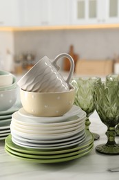 Many different clean dishware, glasses and cup on white table indoors