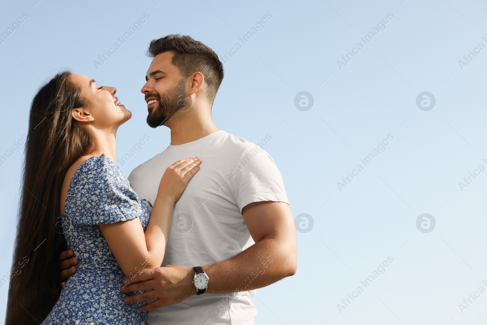 Photo of Romantic date. Beautiful couple spending time together against blue sky, low angle view with space for text