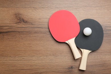 Ping pong rackets and ball on wooden table, flat lay. Space for text